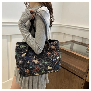 Close-up of colorful butterfly embroidery and JINGPIN logo on black tote bag
