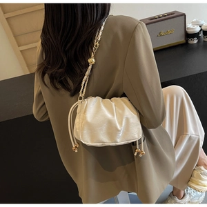 Borsa a nuvola bianca increspata con catena dorata indossata da modella in blazer oliva