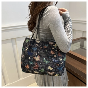 Detail of colorful butterfly pattern embroidery on black canvas tote bag with leather logo
