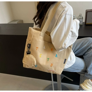 Dettaglio della borsa tote in tela beige con ricamo a lettere colorate e portamonete tondo