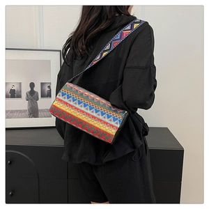 Dettaglio borsa a secchiello boho con ricami geometrici vivaci e tracolla larga decorata