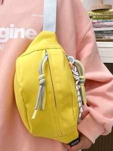 Detailansicht der gelben Nylon-Umhängetasche mit Fashion-Tag auf einem Damenmodell