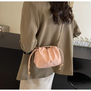 Modella indossa borsa a nuvola rosa con coulisse e sfere dorate e tracolla a catena