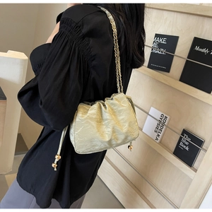 Dettaglio borsa a nuvola plissettata verde chiaro con catena d'oro su scaffale