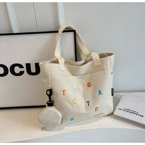 Dettaglio della borsa tote in tela crema con ricami colorati e mini portamonete