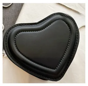 Close-up of black heart-shaped crossbody bag with gold lettering and silver chain strap