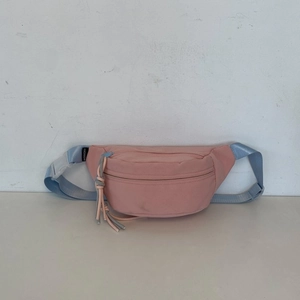 Detail der pinkfarbenen Brusttasche mit Fashion-Label und blauem verstellbarem Gurt