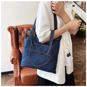 Dettaglio della borsa tote in denim blu con etichetta in pelle e tasca anteriore