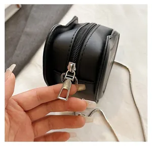 Detailed close-up of the smooth silver zipper and metallic snake chain on heart bag