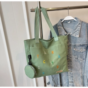 Dettaglio della borsa tote in tela verde con ricami colorati e piccolo portamonete