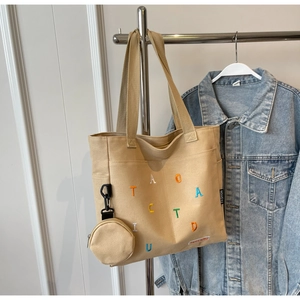 Dettaglio della borsa tote in tela kaki con ricamo colorato e un piccolo borsellino