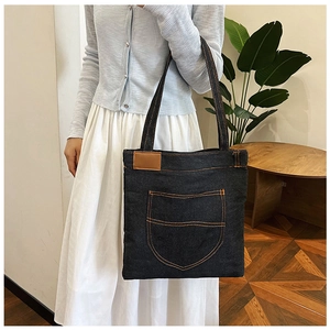 Dettaglio della borsa tote in denim blu con grande tasca a U e cuciture arancioni a contrasto