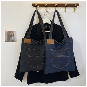 Dettaglio di borse tote in denim grigio scuro e blu navy con cuciture a contrasto e pelle