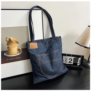 Dettaglio borsa shopper in denim blu scuro con cuciture a contrasto e patch in pelle