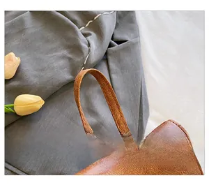 Dettaglio del manico in pelle marrone con cuciture rinforzate sullo zaino casual