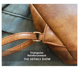 Dettaglio macro della cucitura triangolare rinforzata e fibbia dorata su borsa in pelle marrone