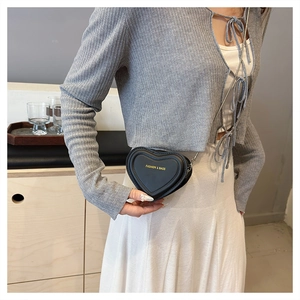 Detail of heart-shaped black crossbody bag with gold chain strap and fashion text