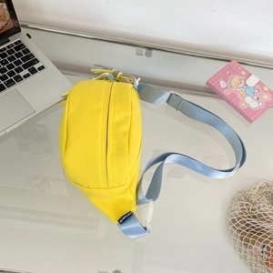 Detail der gelben Streetstyle-Gürteltasche mit blauem Gurt und Fashion-Label auf dem Tisch
