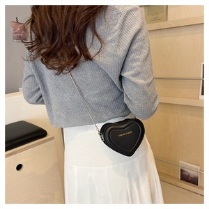 Detailed back view of a model wearing a mini black heart-shaped chain crossbody bag