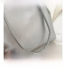 Détail d'un sac cabas argenté en PU avec gravure FASHION et breloque en perles