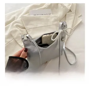Détail du sac argenté à nœud montrant l'intérieur spacieux avec téléphone et portefeuille