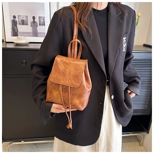 Vista dettagliata di uno zaino vintage marrone abbinato a un outfit con blazer nero