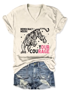 Dettaglio maglietta bianca con scollo a V, stampa a tigre e slogan democracy needs courage