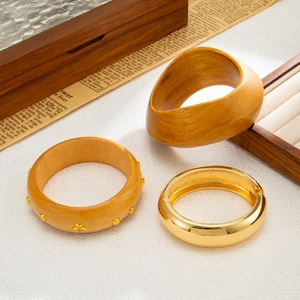 Macro detail of mixed wood and gold metal bracelets with star studs on vintage background