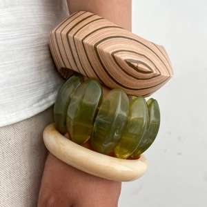 Detail of chunky wooden bangle, olive green resin beads, and cream marble texture bracelets