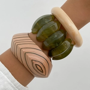 Detail of ethnic style resin bracelets featuring wood texture and translucent olive green charm