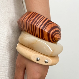 Close-up of a three-piece set featuring striped wood, marble resin, and studded bangles