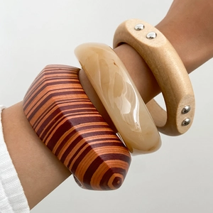 Detail of bohemian set with striped wood, resin, and metal-studded bangles on wrist
