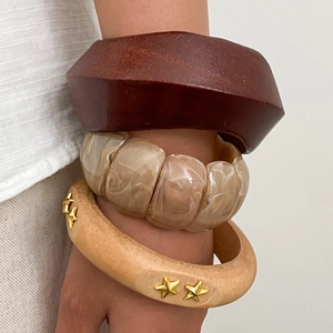 Close-up of bohemian wooden bangles and resin bead bracelet set worn on a wrist