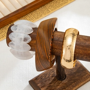 Dettaglio di bracciali in legno, resina marmorizzata e metallo con finitura coccodrillo