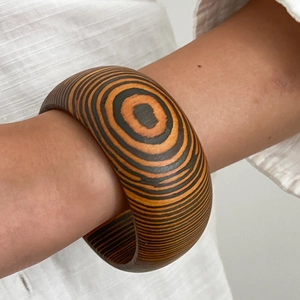 Bracciale largo geometrico in legno con motivi a cerchi annuali arancioni e neri