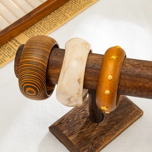 Dettagli di ampi bracciali bohémien con venature del legno, resina marmorea e stelle d'oro