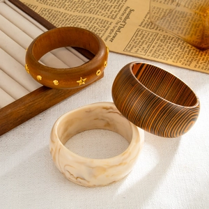 Dettaglio di bracciali vintage in legno e resina marmorizzata in un set elegante e chic