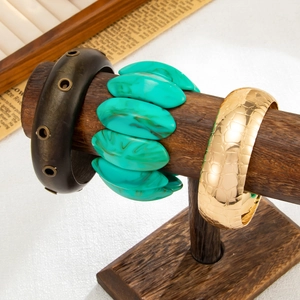 Dettaglio di set bracciali geometrici con perline turchesi e trama a coccodrillo dorata