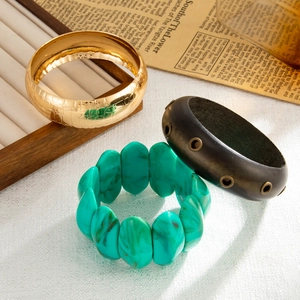 Dettaglio set composto da bracciale dorato, cerchio in resina marrone e perline turchesi