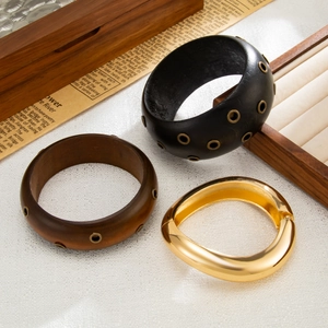 Set di bracciali larghi in finto legno e metallo dorato lucido su sfondo vintage curato