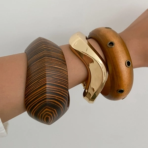 Detailed view of stacked bohemian wooden bangles and wavy gold metal cuff on wrist