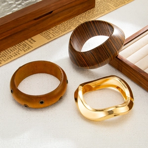 Close-up of geometric wooden and golden metal bracelets set on vintage background