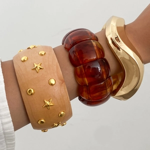 Detail of stacked vintage wood-textured resin bracelets with golden star studs