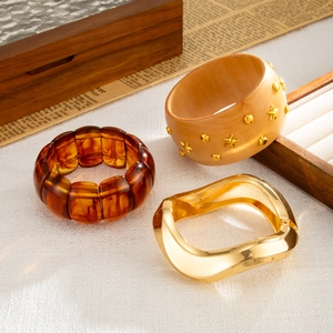 Detail view of retro geometric bracelets with amber resin, studded wood, and wavy gold metal
