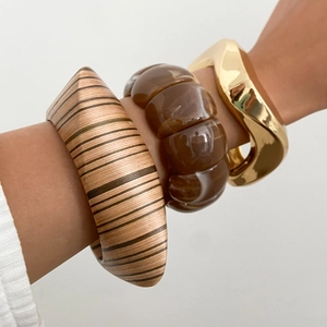 Detail of stacked wood, translucent resin and gold geometric bracelets on wrist