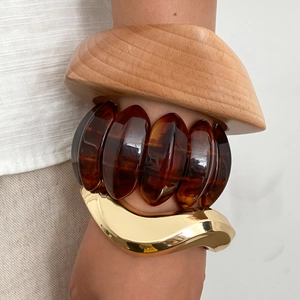 Three-piece stackable bracelet set featuring wood, amber resin, and wavy gold metal cuffs