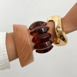 Close-up of retro mixed material bracelets featuring natural wood, amber resin and gold metal