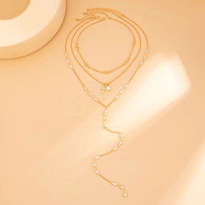 Dettaglio della collana multistrato dorata con croci e perle bianche stile bohémien
