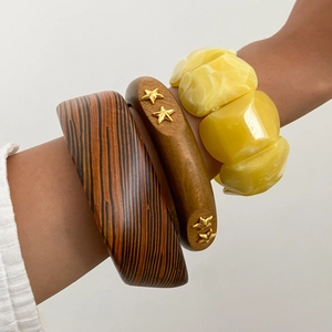 Bracciali sovrapponibili in resina e venature del legno con stelle dorate sul polso