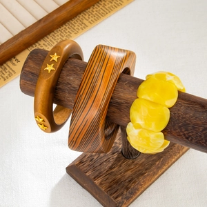 Dettaglio di bracciali in resina e legno esposti su un supporto in legno scuro